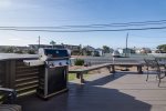 Propane Weber grill, with bench seating and dining table on front deck.